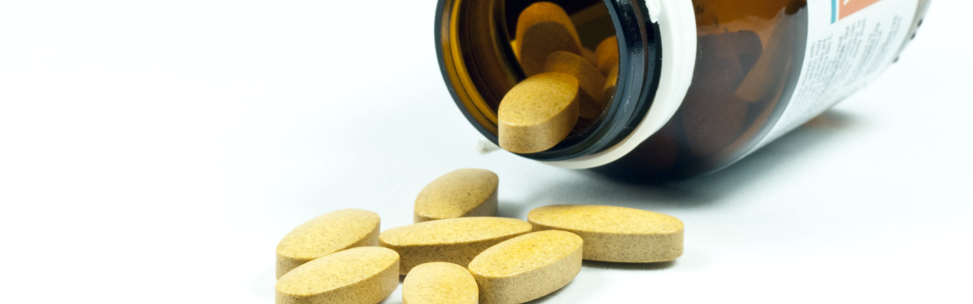 yellow tablets inside and outside of a medicine bottle